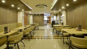 Un interior de restaurante moderno con cabinas y mesas, paneles de madera y un ambiente limpio y bien iluminado.