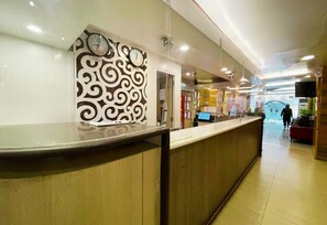A reception area with a clock, a decorative wall, and a counter. - Hotel 99 Monumento Caloocan (Caloocan)