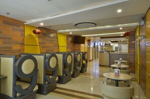 A hotel lobby with seating areas, a reception desk, and a kitchen in the background. - Hotel 99 Monumento Caloocan (Caloocan)
