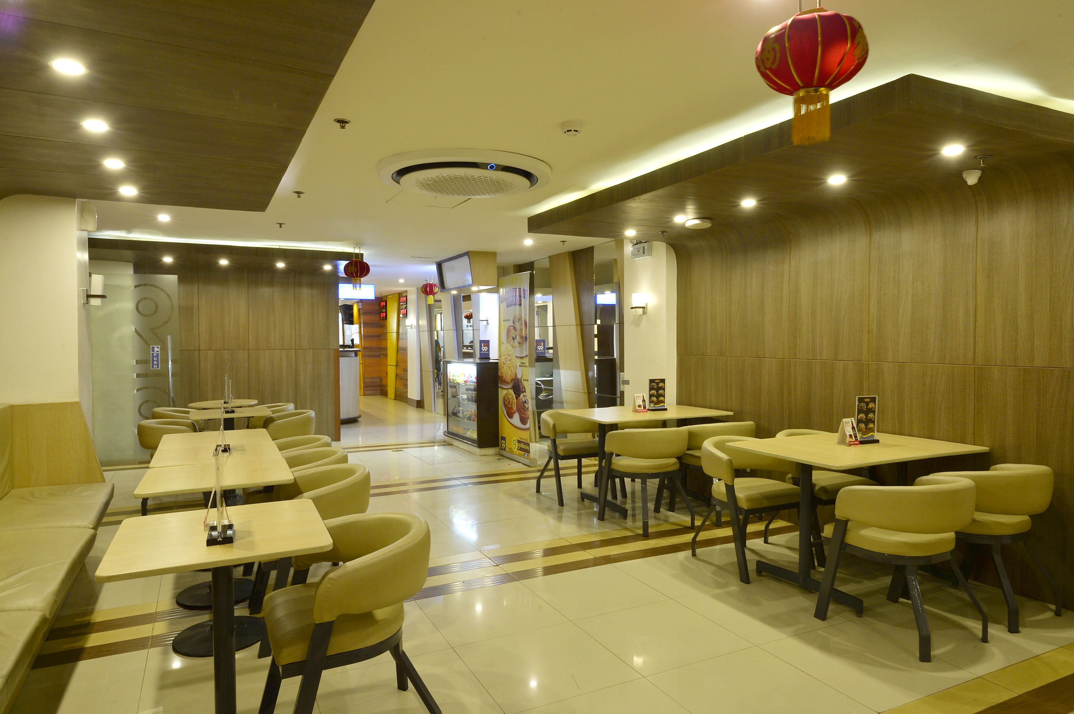 A modern restaurant with multiple dining tables and chairs, a ceiling with recessed lighting, and a red lantern hanging from the ceiling.