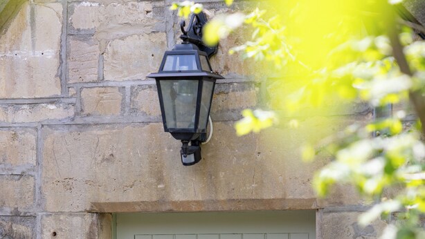 A light green door with the number 5, a metal latch, and a black lantern above it, set against a stone wall. - The Coach House (Corsham)
