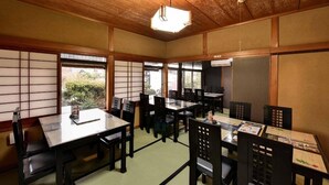 A traditional Japanese room with tatami flooring, wooden sliding doors, and a low ceiling. Tables and chairs are arranged for dining. - BENIKEA Yufuin Kinrinko Hotel Museum (Yufuin)
