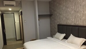 Una habitación de hotel con cama, armario, puerta y aire acondicionado de pared.