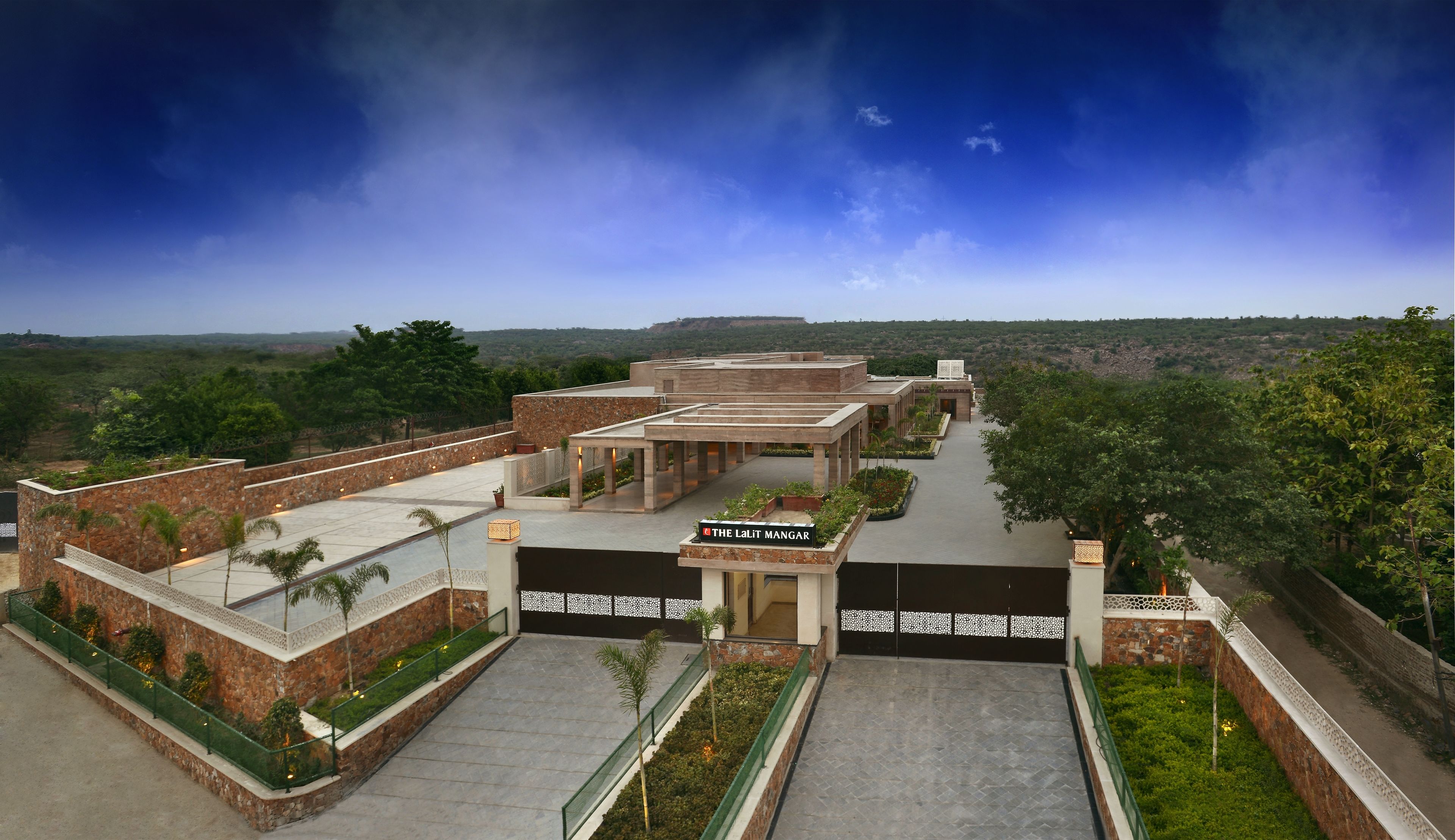 Ein Hotel mit Natursteinfassade, einem überdachten Außenbereich und Blick auf die umliegende Landschaft.