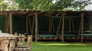 Ein rustikaler Außenbereich mit hölzernen Bänken und Liegestühlen unter einer Holzpergola.