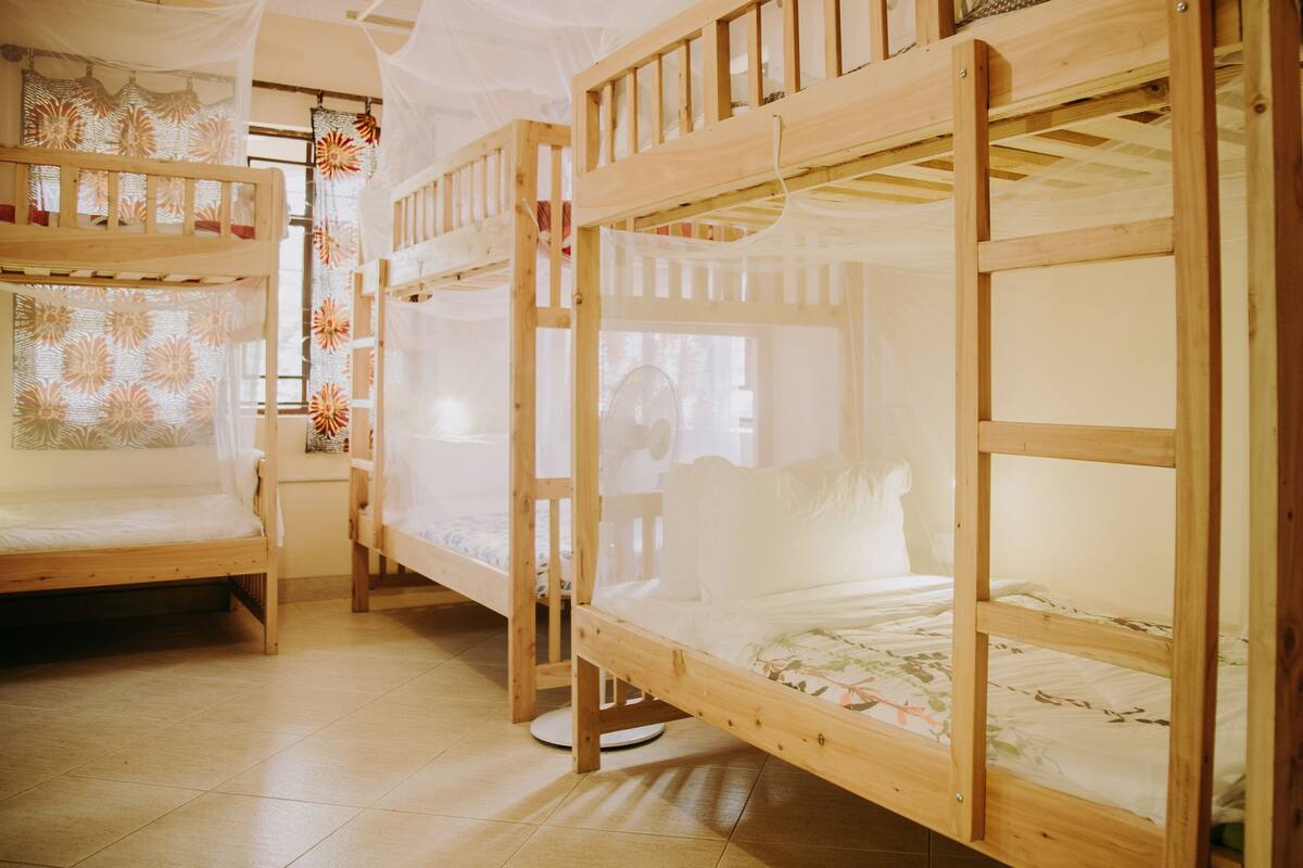 Ein Zimmer mit drei Etagenbetten, jeweils mit Holzrahmen und weißer Bettwäsche.