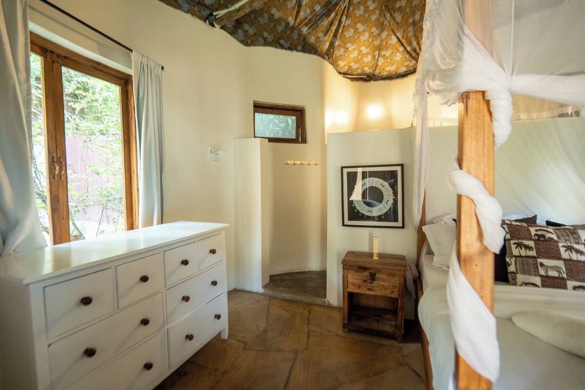 Ein Schlafzimmer mit einem hölzernen Bett, einem weißen Schminktisch, einem kleinen Nachttisch aus Holz und einem gerahmten Bild an der Wand.