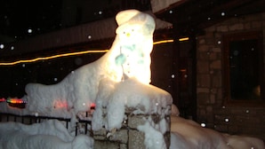 Estructura de piedra cubierta de nieve con una fuente de luz en su interior, rodeada de nieve.