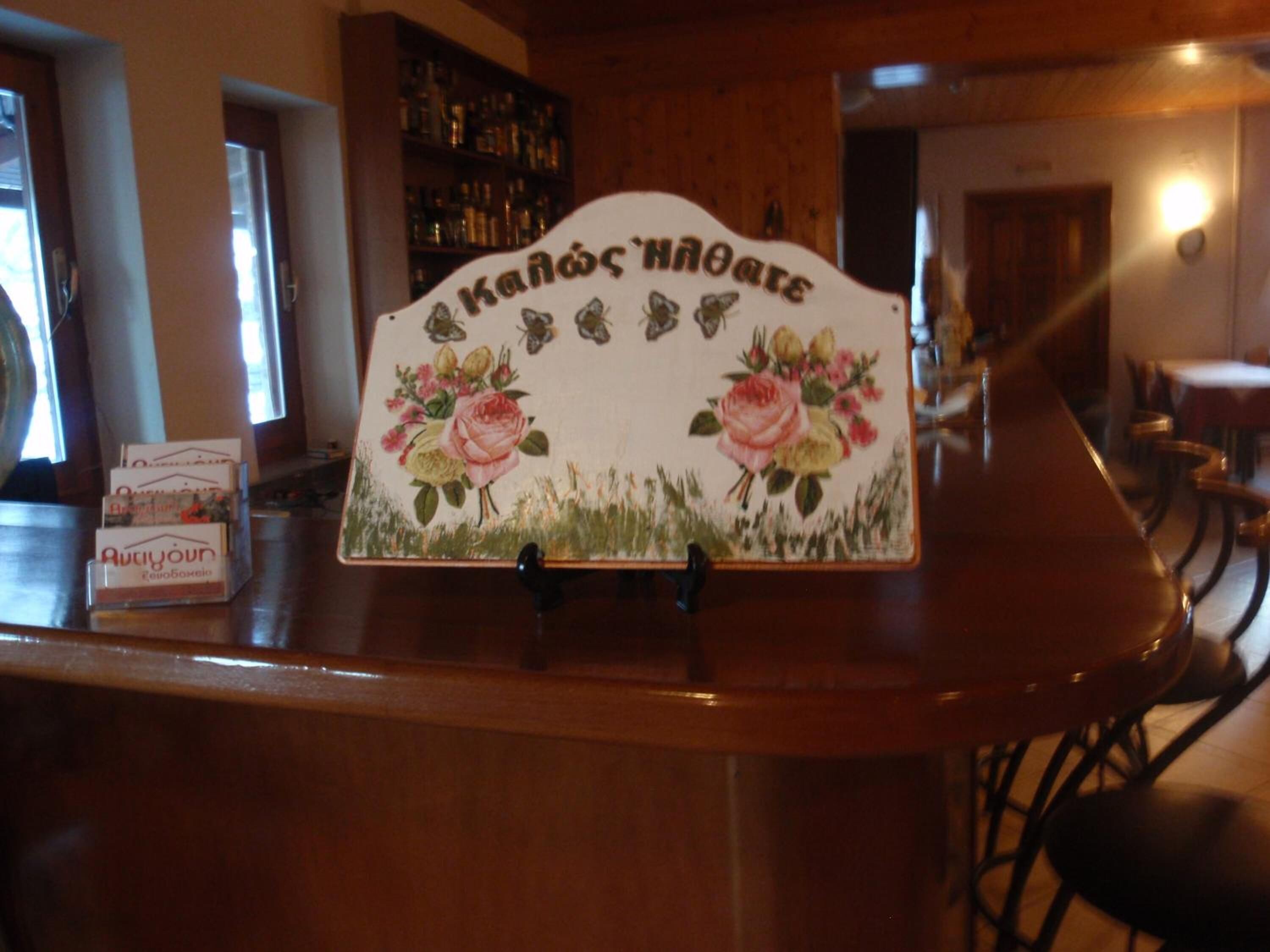 A wooden counter with a decorative sign featuring floral designs and text.