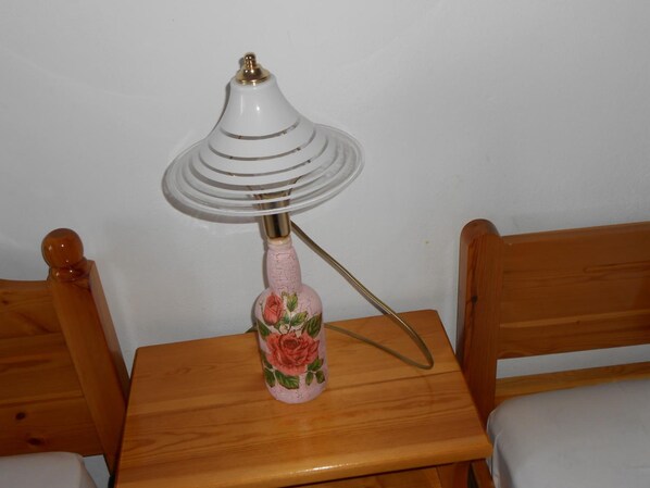 Una pequeña mesa de madera con una lámpara que presenta un diseño floral en su base.