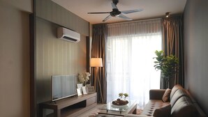 Uma sala de estar moderna com televisão de tela plana, ventilador de teto, sofá, mesa de centro e uma janela grande com cortinas.