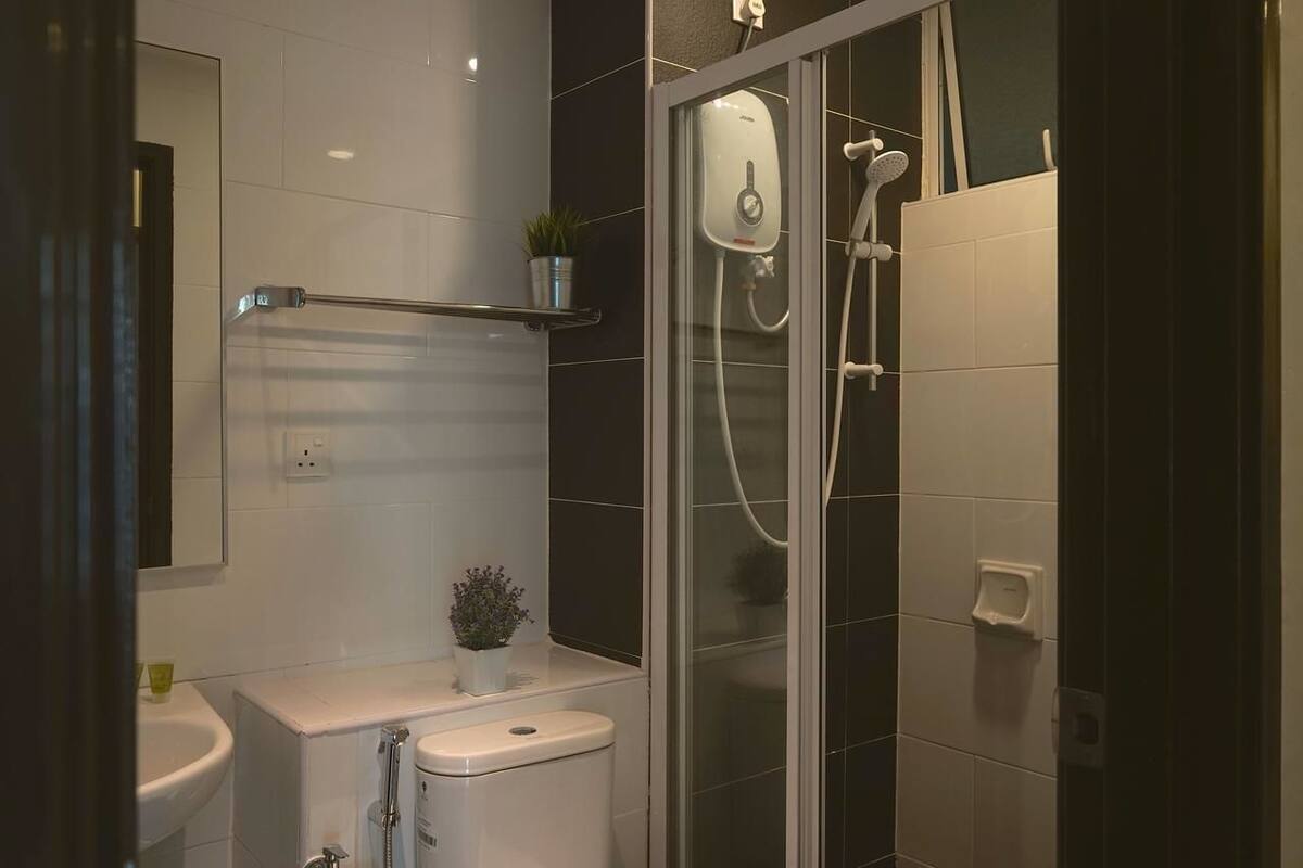 A modern bathroom with a glass shower enclosure, a white sink, and a small potted plant on the countertop.