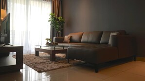 Uma sala de estar moderna com um sofá de couro, uma mesa de centro de vidro e uma planta grande.
