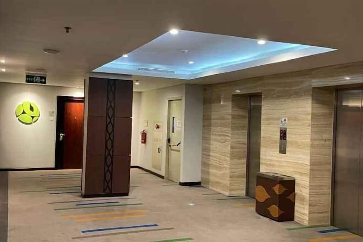 A hotel lobby with a modern design, including a skylight, elevators, and a reception area.