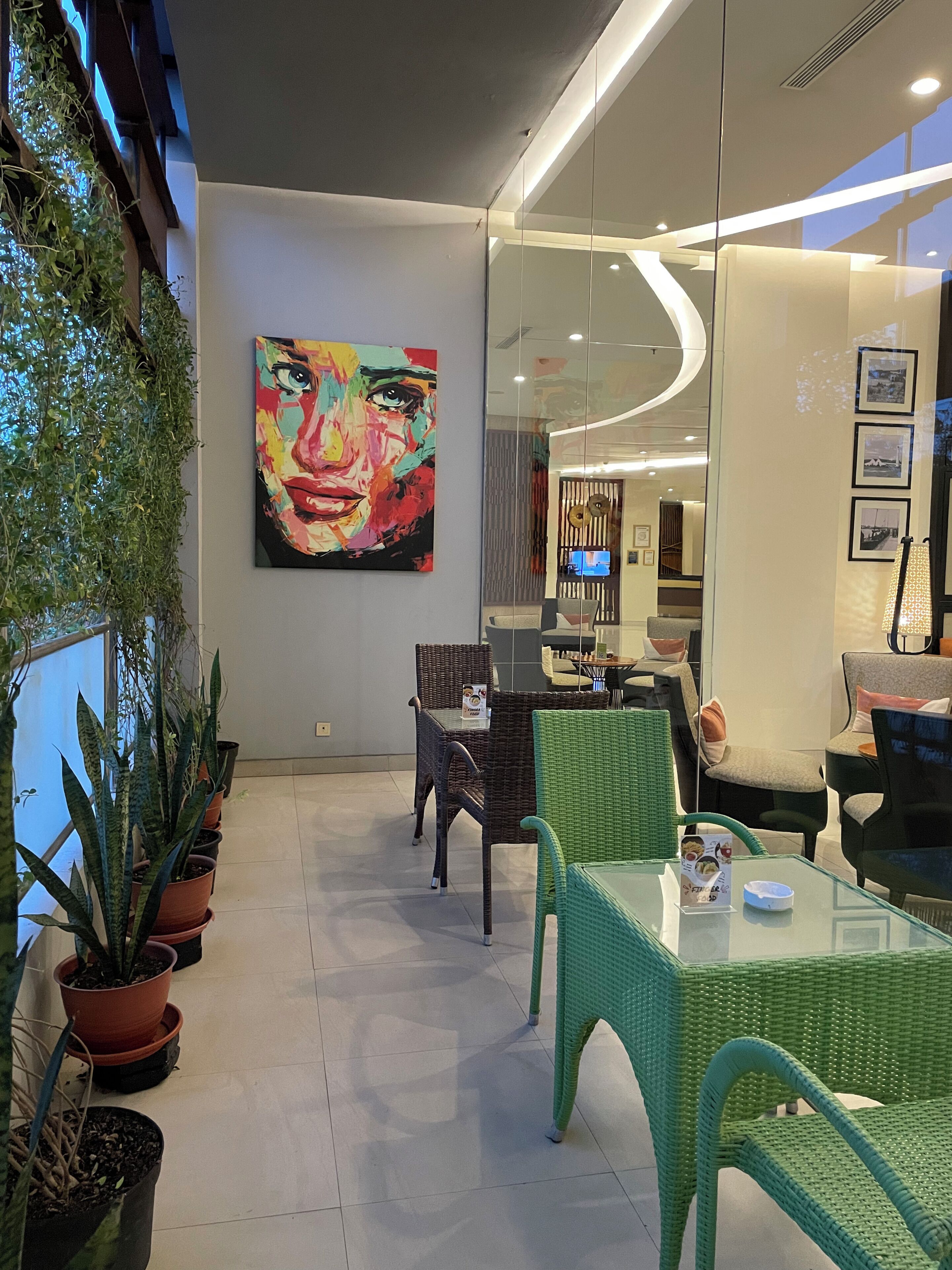 A modern interior with a glass wall, wicker furniture, and a large abstract painting.