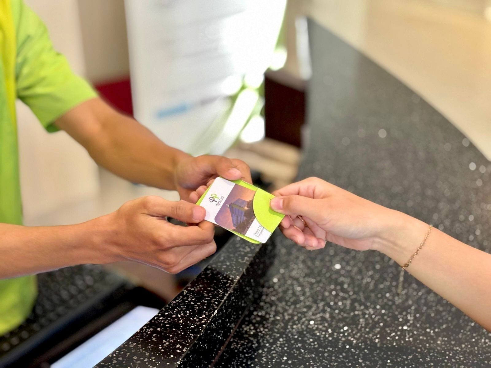 A person receiving a card from another person at a counter.