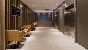 Un moderno vestíbulo de hotel con un mostrador de recepción amplio, una zona de estar y ascensores.