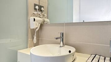 A modern bathroom with a large mirror, a white sink, and a hairdryer mounted on the wall.