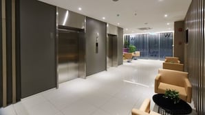 Un moderno vestíbulo de hotel con recepción, ascensores y asientos.