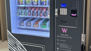Máquina expendedora con pantalla digital y teclado, repleta de diversas botanas y bebidas.