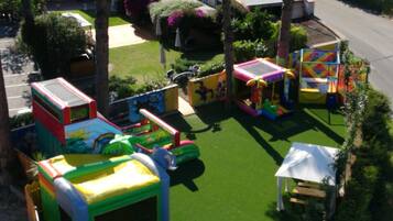Children can play on the inflatable slides and climbing elements, or enjoy the playhouse and shaded area.