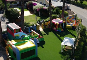 Zona de juegos al aire libre con estructuras hinchables y una carpa blanca.