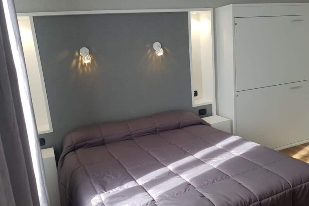 A bedroom with a bed, bedside lamps, and a wardrobe.
