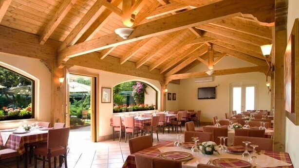 Ein Restaurant mit Holzbalken, gedeckten Tischen und Blick ins Grüne.