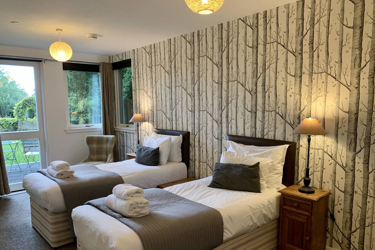 Ett hotellrum med två sängar, ett stort fönster och utsikt över omgivningarna.