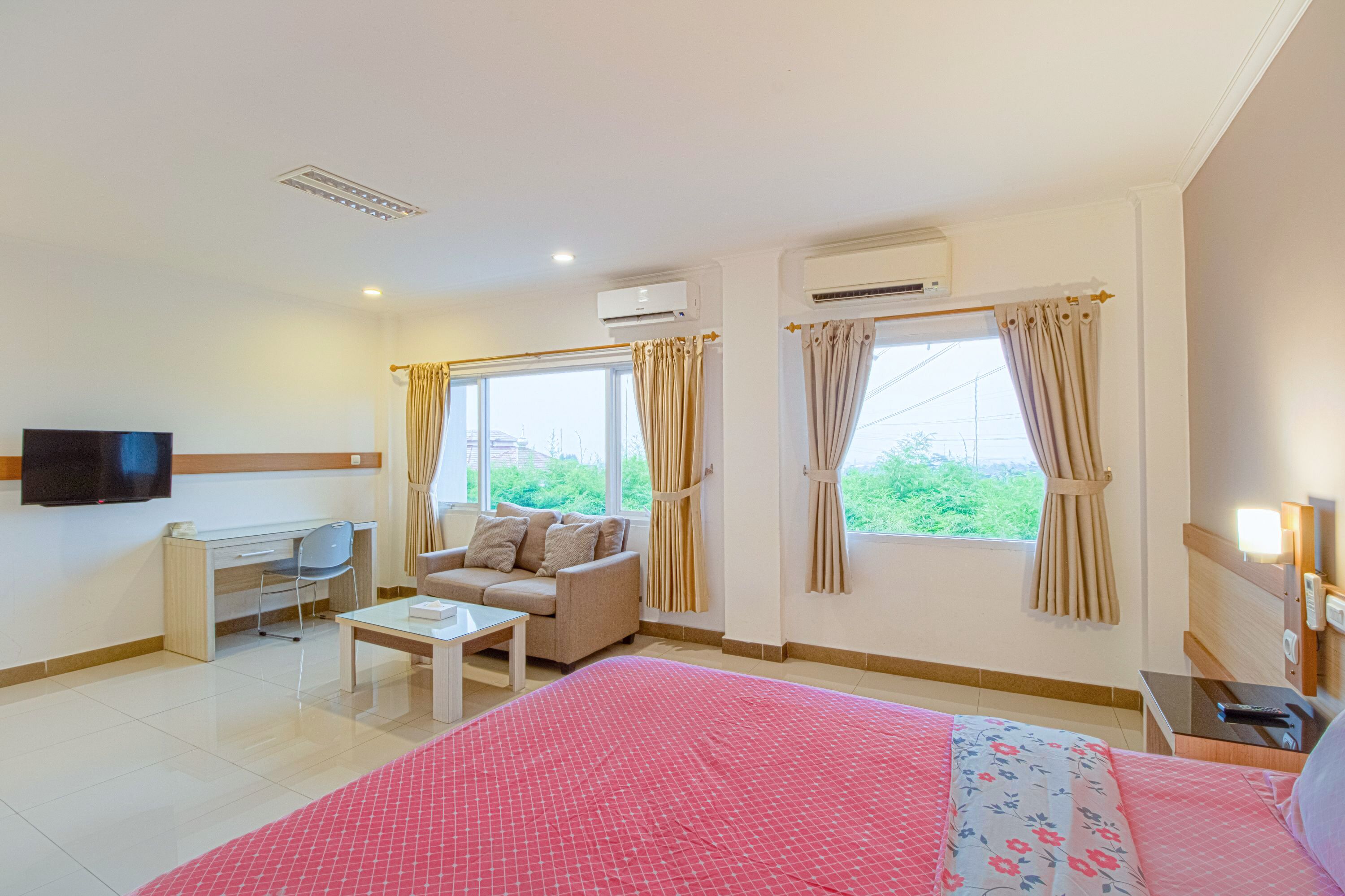 A hotel room with a bed, a sofa, a desk, and a TV.