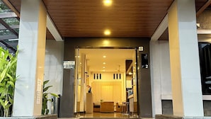 A hotel entrance with a wooden overhang, a staircase leading to the lobby, and a sign indicating the room number.