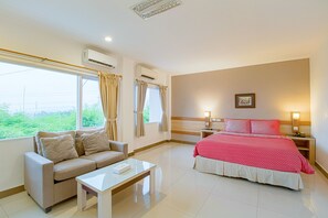Una habitación de hotel con una cama, un sofá, una mesita de centro y una mesita de noche.