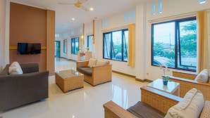 A spacious living area with wicker furniture, large windows, and a ceiling fan.