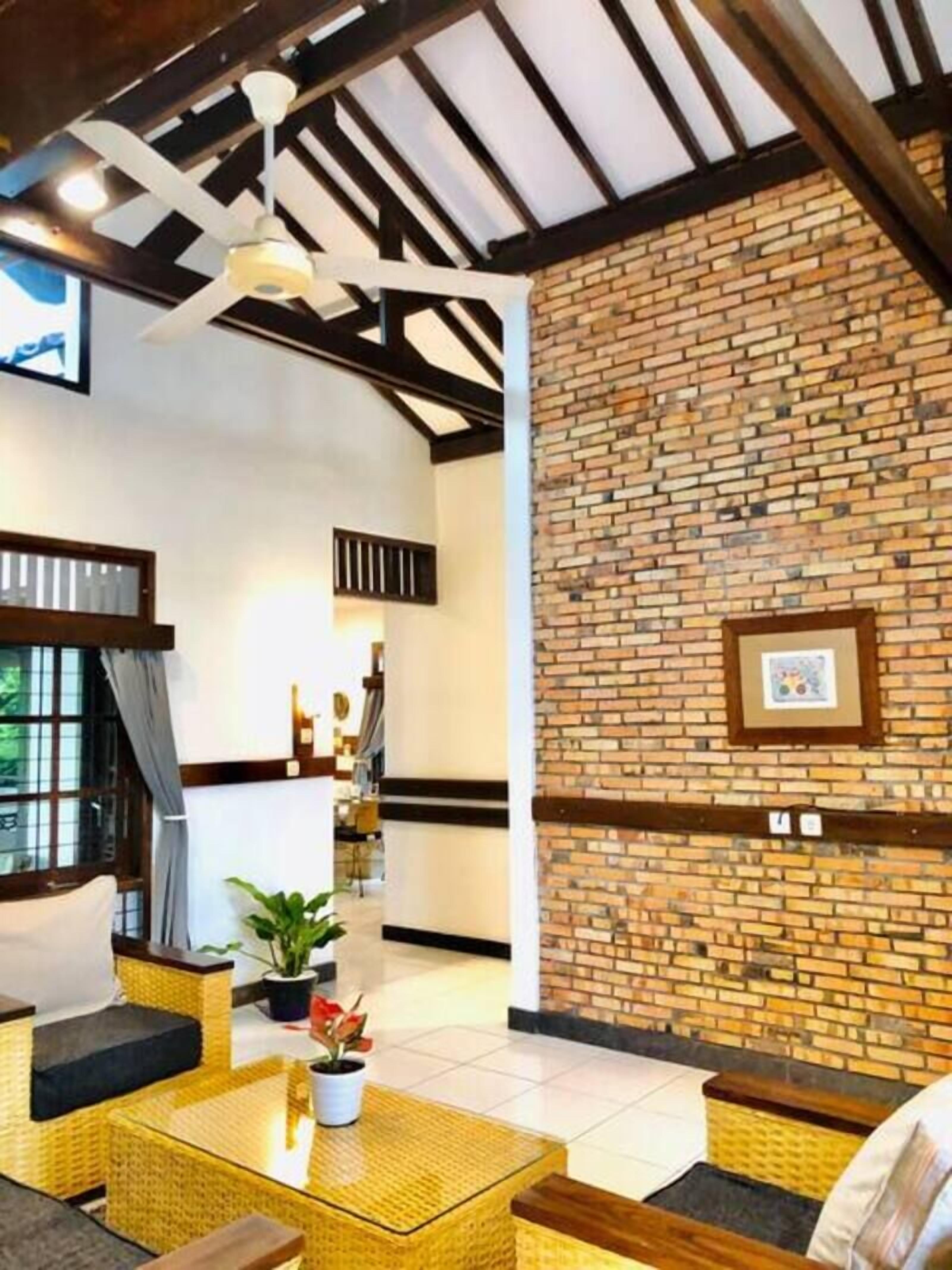 A cozy indoor seating area with wicker furniture, a brick wall, and a ceiling fan.