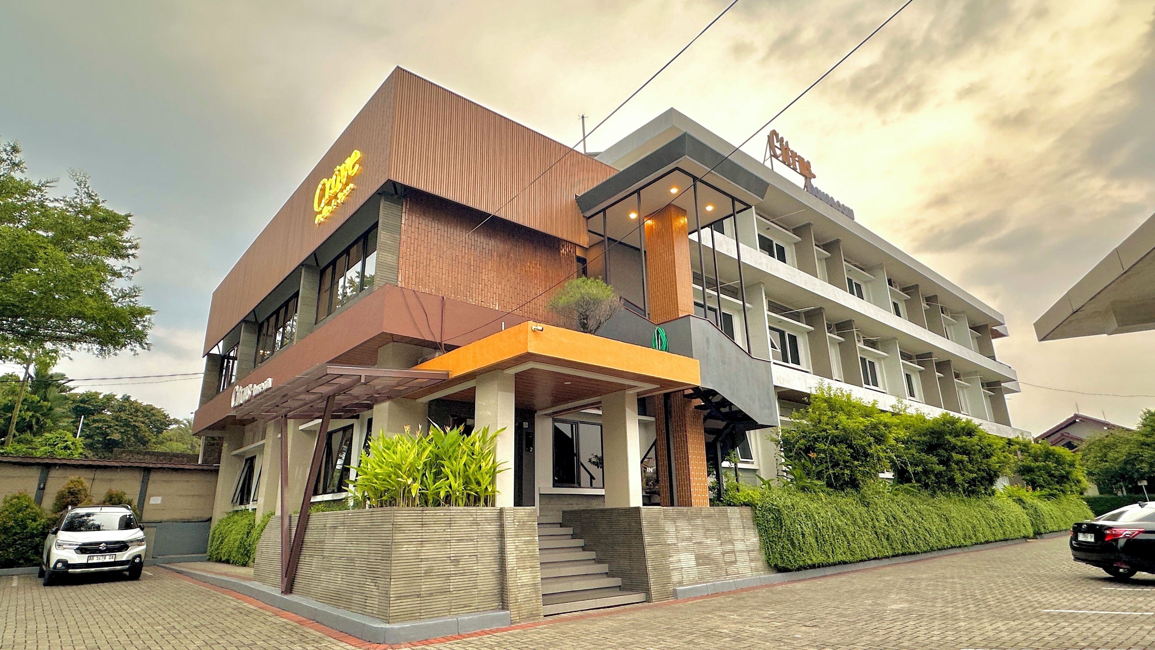 A modern hotel with a prominent yellow sign, a covered entrance, and a staircase leading to the main building.