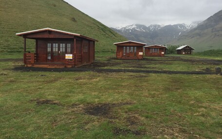Three wooden cabins with a mountain backdrop.