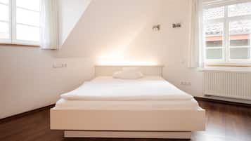 Un dormitorio moderno con una cama grande, techo inclinado y una ventana con cortinas.
