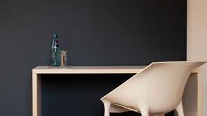 A modern desk with a white chair, a dark wall, and a glass bottle on the desk. - Brauerei Gasthof Krone (Tettnang)