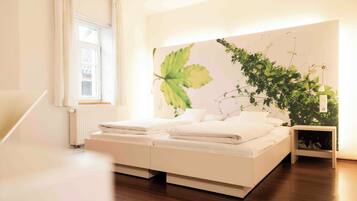 Een slaapkamer met een bed, een raam, een radiator en een plant aan de muur.
