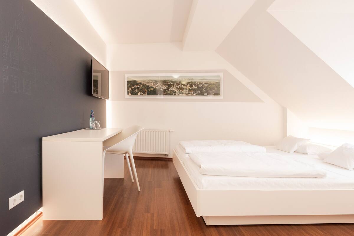 A modern bedroom with a bed, a desk, and a chair.