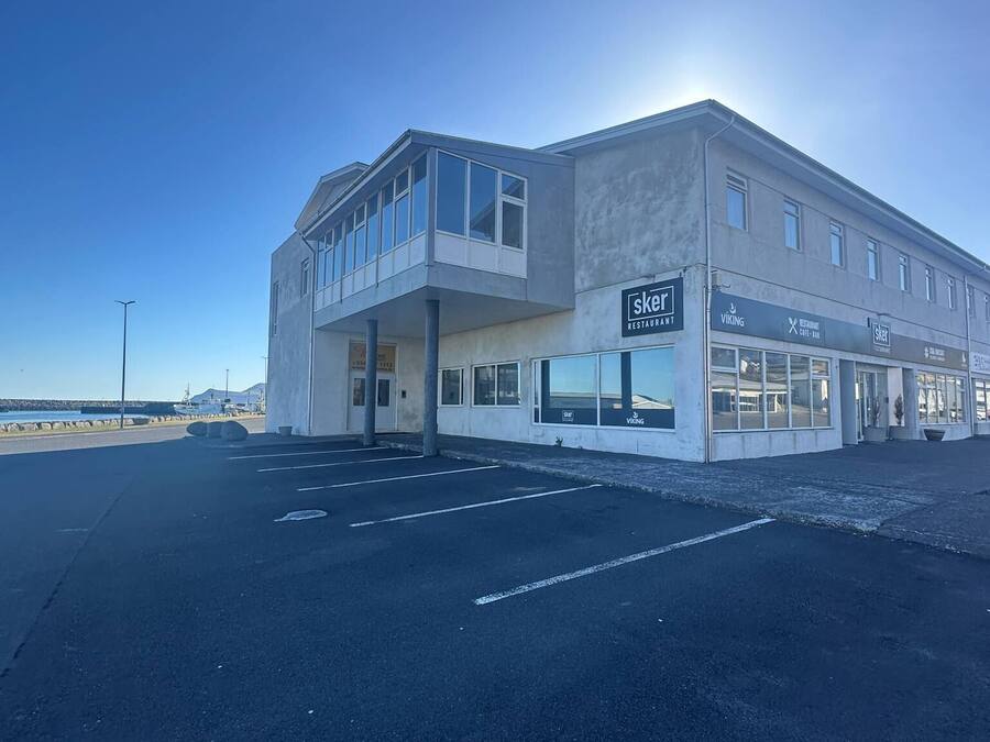 Un edificio con un restaurante en la planta baja llamado 'Skær' y un segundo piso con grandes ventanales.