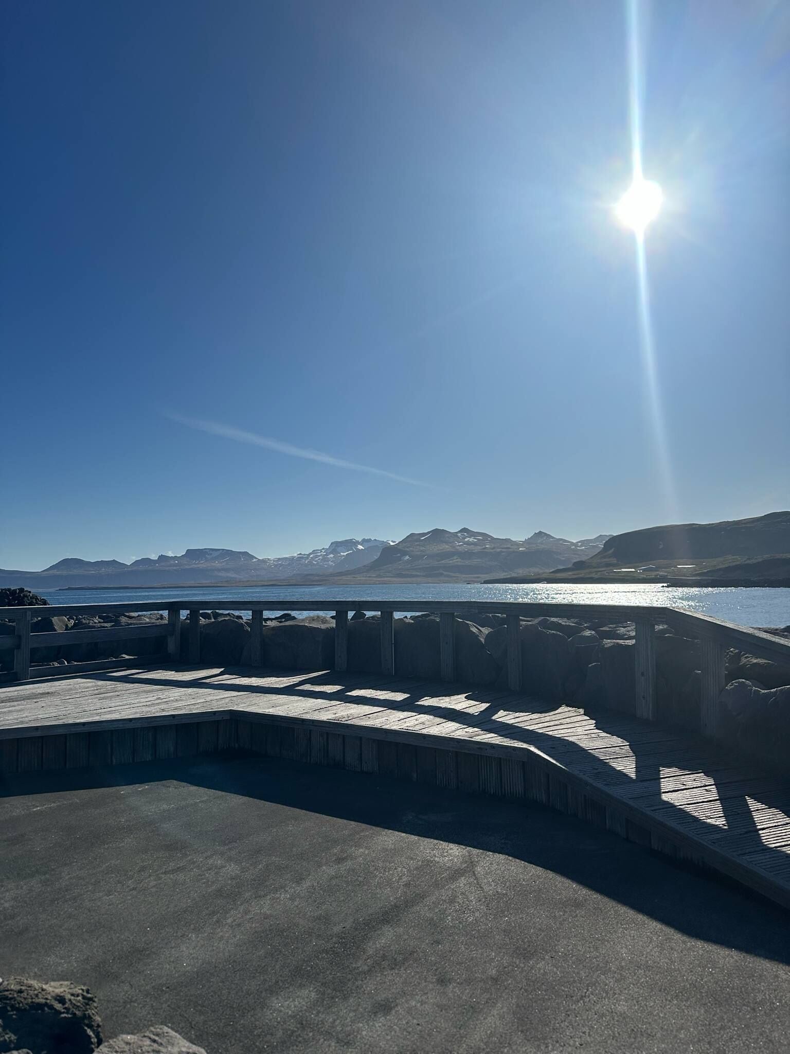 Une jetée en bois s’étendant sur une étendue d’eau, avec des montagnes en arrière-plan.