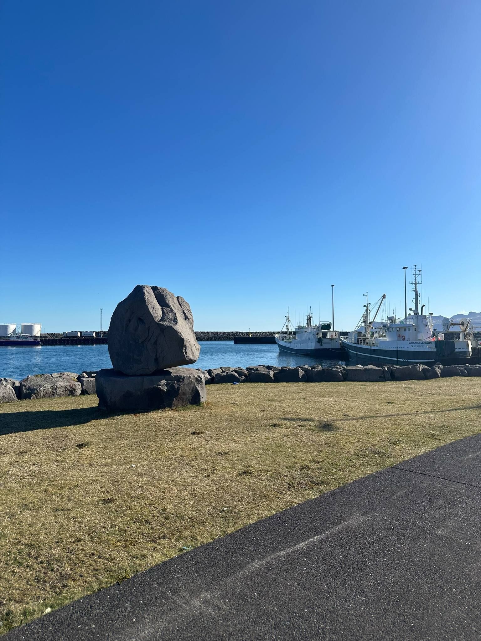 A rocky outcrop near a harbor with a clear blue sky.