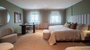 Une chambre moderne avec un grand lit, un miroir rond, une petite table et un fauteuil confortable.