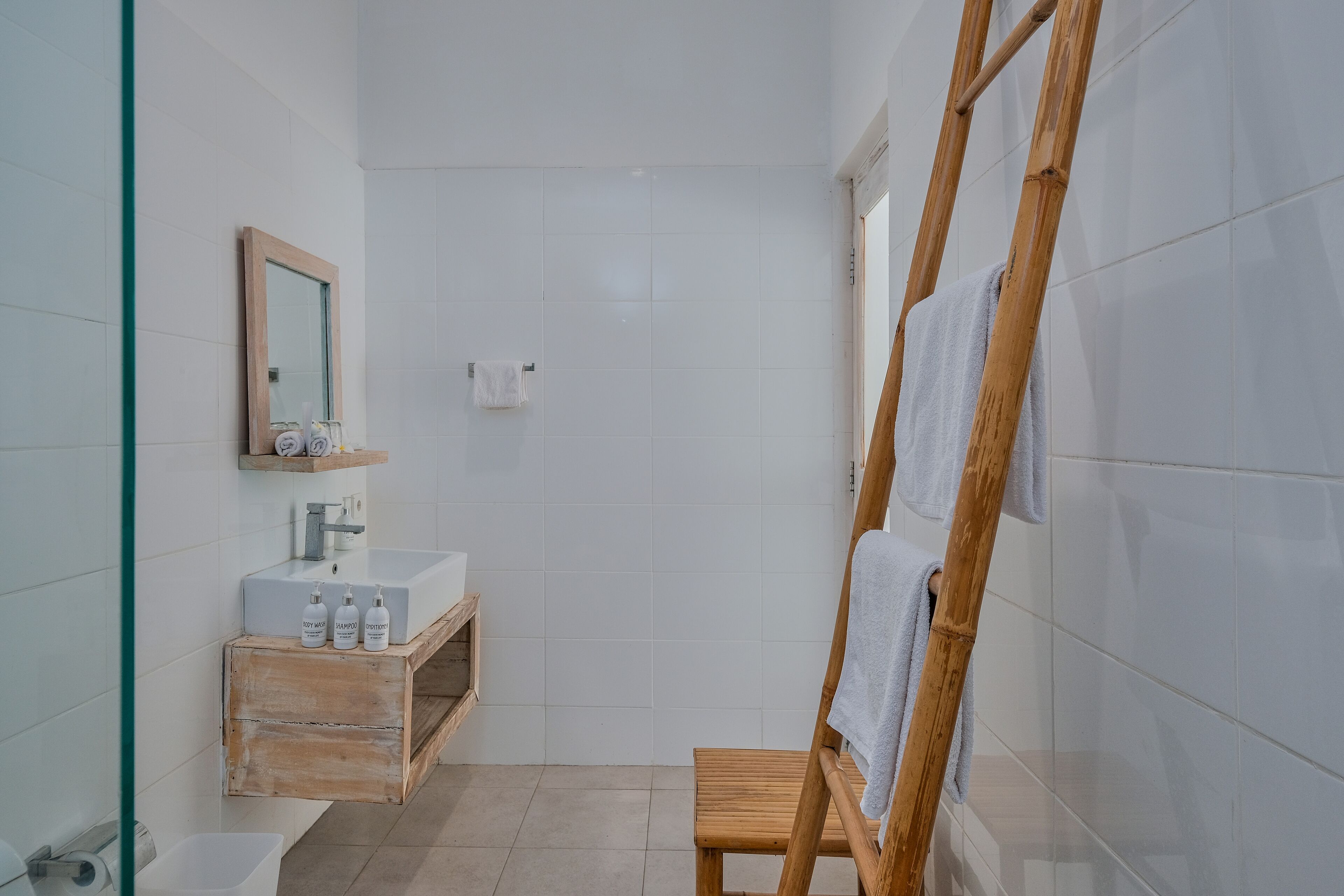A bathroom with a wooden vanity, a mirror, and a shower area.