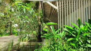 A lush garden with various plants and a wooden structure. - MYAMO Beach Lodge (Sumbawa Barat)