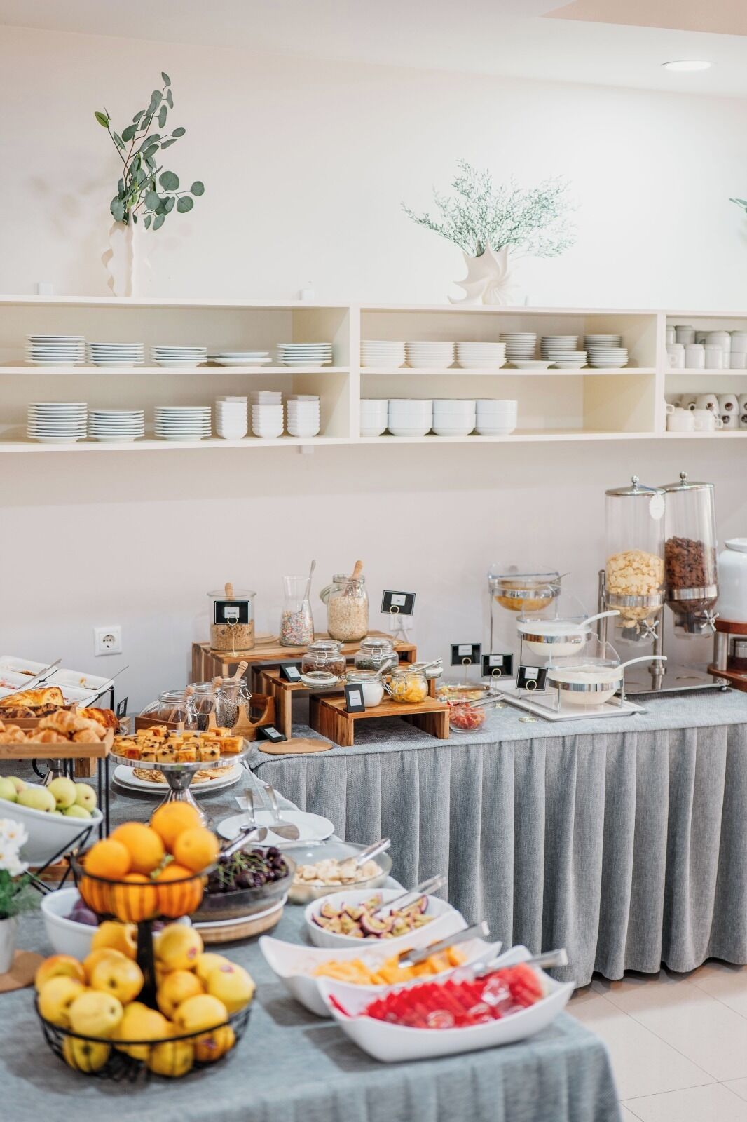 Ein reichhaltiges Buffet mit verschiedenen Speisen sowie Teller und Schüsseln auf Regalen.
