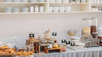 Ein reichhaltiges Buffet mit verschiedenen Speisen sowie Teller und Schüsseln auf Regalen.