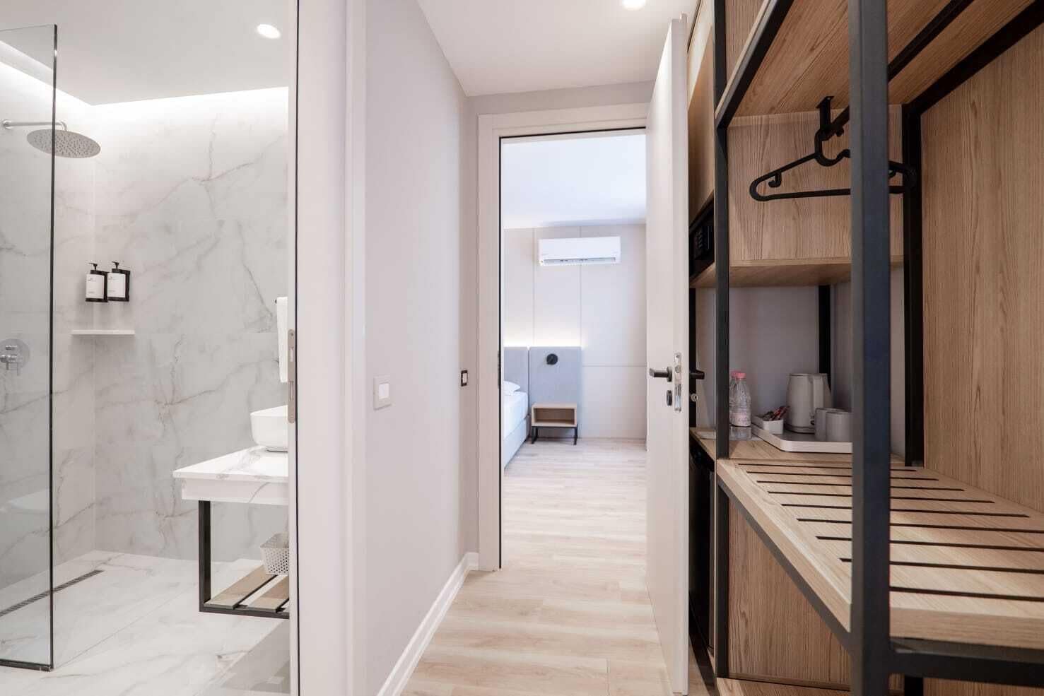 Un baño moderno con cabina de ducha de vidrio, un lavabo blanco y un mueble de tocador de madera.