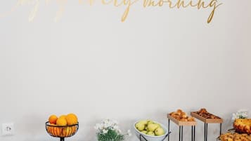 A breakfast buffet with various fruits, pastries, and a decorative sign saying 'Enjoy every morning.'